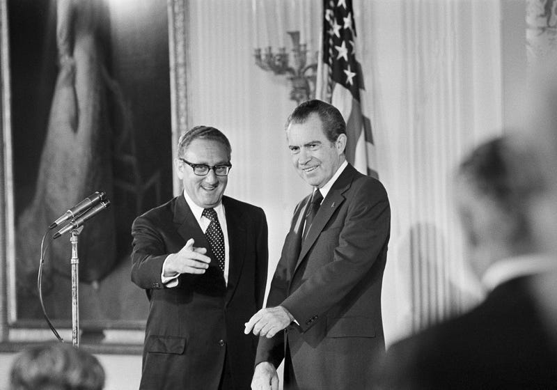 FILE - Secretary of State Henry Kissinger, left, gestures to the audience in the East Room of the White House, Sept. 22, 1973, as President Richard Nixon watches, in Washington. Kissinger had just been sworn in as the 56th secretary of state. Kissinger, the diplomat with the thick glasses and gravelly voice who dominated foreign policy as the United States extricated itself from Vietnam and broke down barriers with China, died Wednesday, Nov. 29, 2023. He was 100. (
