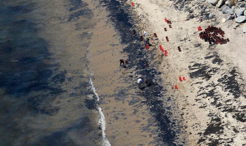 FILE - Volunteers fill buckets with oil near Refugio State Beach after an oil spill north of Goleta, Calif., May 20, 2015. A judge has approved a $230 million lawsuit settlement by the owners of a pipeline that spilled more than 140,000 gallons of crude oil into the ocean off California in 2015.