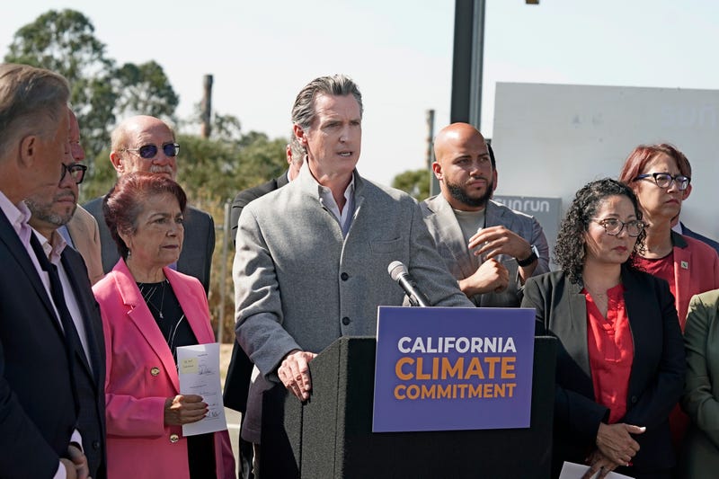 FILE - Gov. Gavin Newsom, center, is flanked by state lawmakers while discussing the package of legislation he signed that accelerates the climate goals of the nation's most populous state, at Mare Island in Vallejo, Calif., Friday, Sept. 16, 2022. Newsom opposes Proposition 30, which would raise taxes on people making more that $2 million to pay for electric vehicle infrastructure and firefight resources.