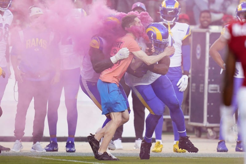A protester is hit by Los Angeles Rams defensive end Takkarist McKinley, middle left, and linebacker Bobby Wagner during the first half of an NFL football game between the San Francisco 49ers and the Rams in Santa Clara, Calif., Monday, Oct. 3, 2022.
