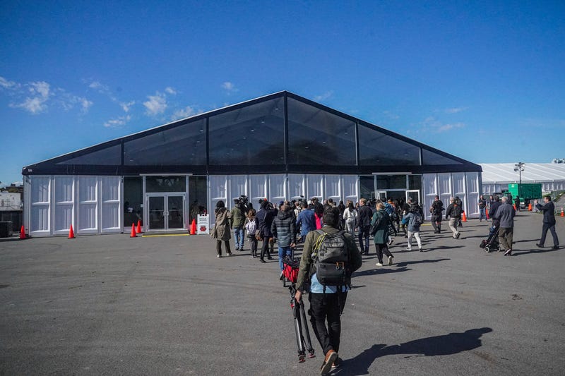 Media arrive for a tour at the Randall's Island Humanitarian Emergency Response and Relief Center, center, a complex of giant tents to serve as a temporary shelter for migrants being bused into the city by southern border states, Oct. 18, 2022