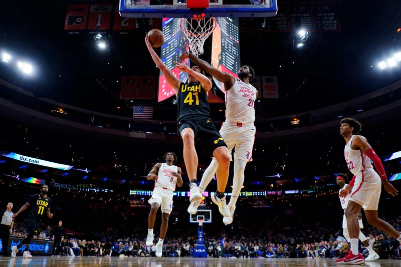 Utah Jazz's Collin Sexton, right, goes up for a shot past Philadelphia 76ers' Joel Embiid during the first half of an NBA basketball game, Sunday, Nov. 13, 2022, in Philadelphia.