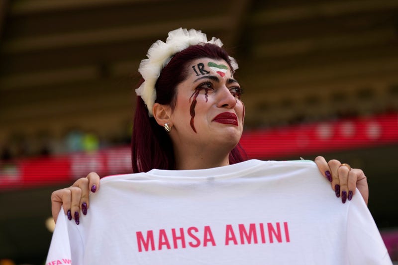 An Iran team supporter cries as she holds a shirt that reads "Mahsa Amini" prior to the start of the World Cup group B soccer match between Wales and Iran, at the Ahmad Bin Ali Stadium in Al Rayyan, Qatar, Nov. 25, 2022.