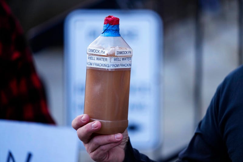 Craig Stevens holds a bottle of brown water as he speaks with members of the media outside the Susquehanna County Courthouse in Montrose, Pa., Tuesday, Nov. 29, 2022. Pennsylvania's most active gas driller has pleaded no contest to criminal environmental charges in a landmark pollution case. Houston-based Coterra Energy Inc. entered its plea Tuesday.