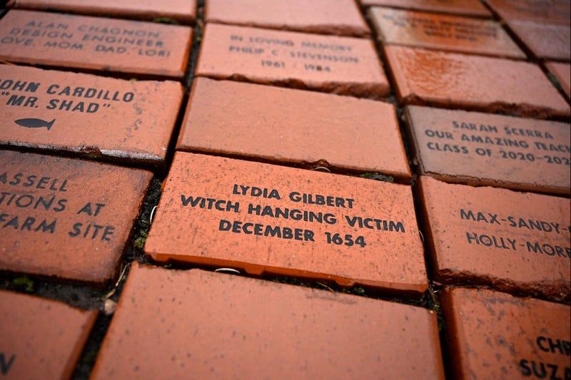In this Tuesday, Jan. 24, 2023 photo, a brick memorializing Lydia Gilbert is placed in a town Heritage Bricks installation in Windsor, Conn. In 1651, an accident during a local militiamen training exercise led to the accusation of witchcraft and hanging of Lydia Gilbert