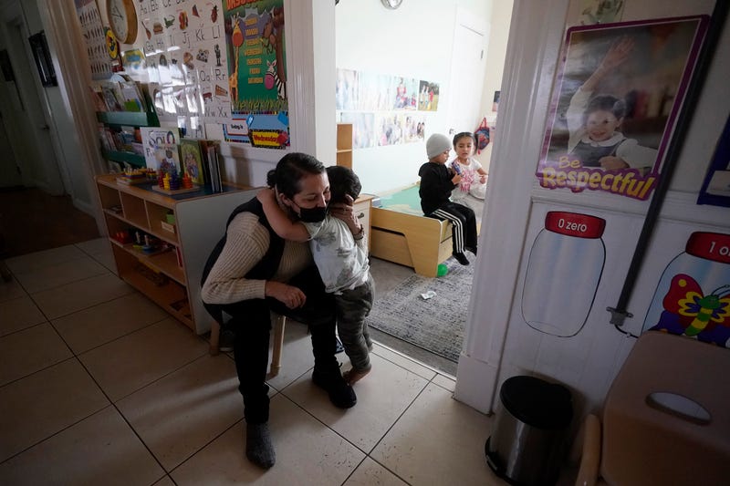 Patricia Moran gets a hug from one of the children at her child care facility in San Jose, Calif., Wednesday, Feb. 15, 2023. California pays for low-income people to have child care. Two years ago, Gov. Gavin Newsom and the state Legislature agreed to spend enough money so that 200,000 more people could get childcare. This year, because California is facing a budget deficit, Newsom has proposed delaying funding for 20,000 new slots for one year, which has angered child care workers, who say the reason many slots have gone unfilled is because the administration is slow to hand out the new money. 