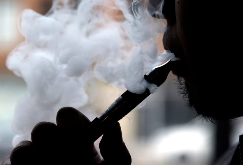 In this April 23, 2014 file photo, a man smokes an electronic cigarette in Chicago. Food and Drug Administration officials on Friday, Feb. 24, 2023 pledged a reset in the agency’s tobacco program, responding to criticisms that a lack of direction has hampered federal efforts to regulate cigarettes, vaping devices and other industry products.