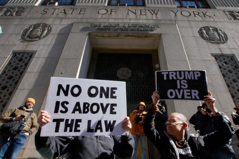 People hold up posters as part of a protest in front of the courthouse ahead of former President Donald Trump's anticipated indictment on Monday, March 20, 2023, in New York. 