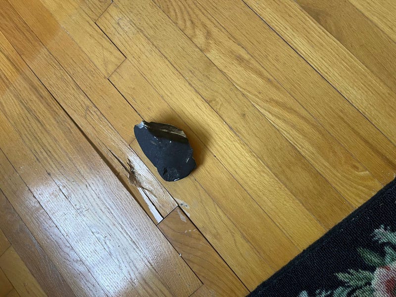 This image provided by Hopewell Township Police Department shows a metallic object believed to be a meteorite on a hardwood floor at a residence in Hopewell Township, N.J.