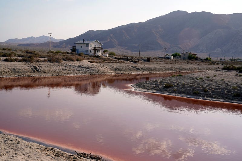 FILE - Clouds and nearby mountains are reflected in a polluted canal, once used as a boating dock, along the Salton Sea in Desert Shores, Calif., on July 14, 2021. California Gov. Gavin Newsom has proposed the purchasing power of the state to purchase large amounts of new renewable energy, including from offshore wind and geothermal power plants. That could allow more geothermal power plants be built near the Salton Sea.