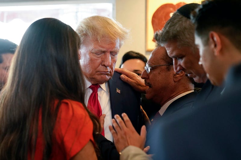Former President Donald Trump prays with pastor Mario Bramnick, third from right, and others at Versailles restaurant on Tuesday, June 13, 2023, in Miami. Trump appeared in federal court Tuesday on dozens of felony charges accusing him of illegally hoarding classified documents and thwarting the Justice Department's efforts to get the records back.