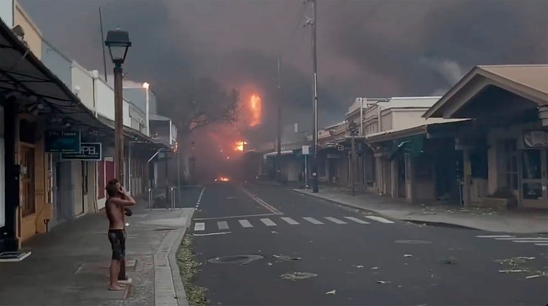 People watch as smoke and flames fill the air from raging wildfires on Front Street in downtown Lahaina, Maui on Tuesday, Aug. 8, 2023.