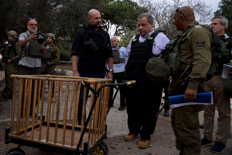 Chris Christie, center right, looks at a baby carriage as he visits Kibbutz Kfar Azza