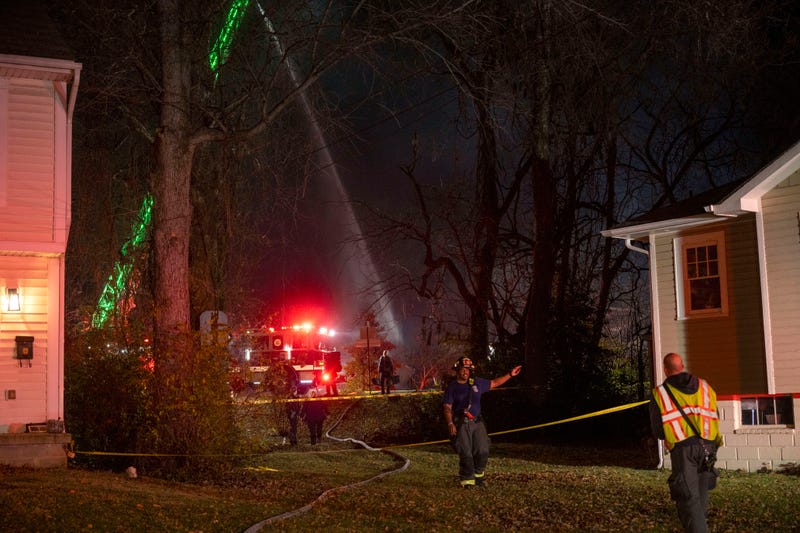 Fire and police officials walk around the scene of a house explosion
