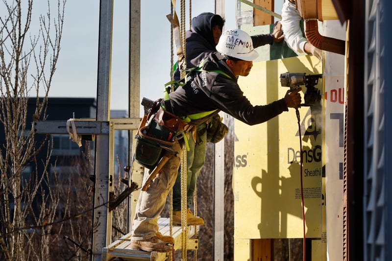 Workers apply sheathing to a building
