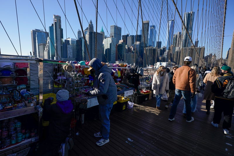 Pedestrians pass by vendors on the Brooklyn Bridge in New York, Tuesday, Jan. 2, 2024