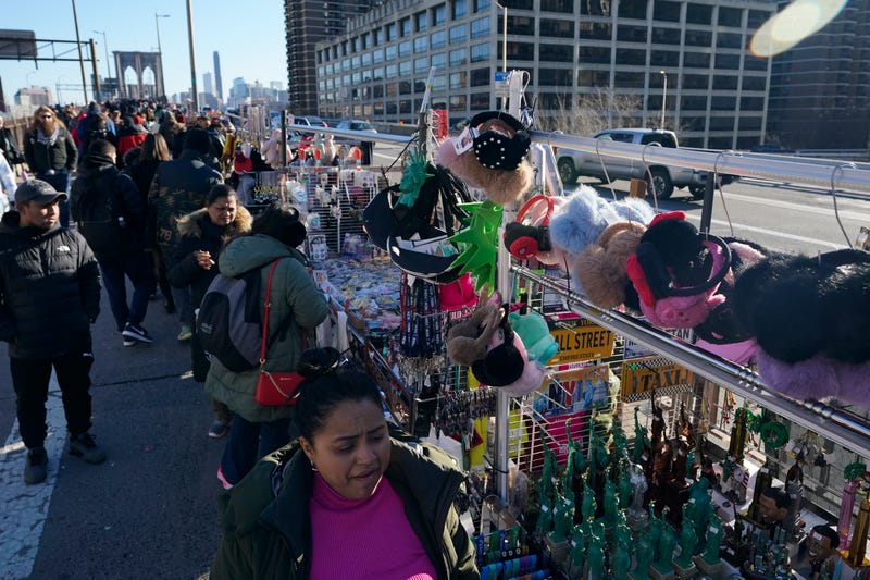Pedestrians pass by vendors on the Brooklyn Bridge in New York, Tuesday, Jan. 2, 2024