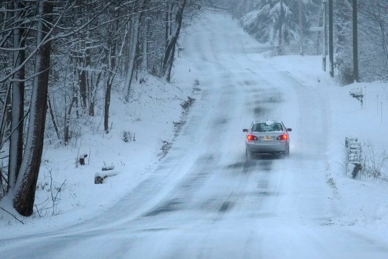A car treks down a snow-covered road, Sunday, Jan. 7, 2024.