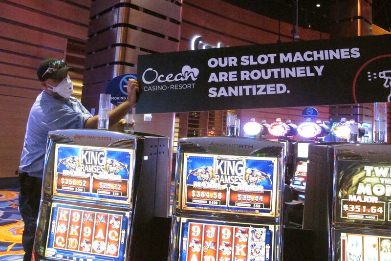 A worker at the Ocean Casino Resort in Atlantic City, New Jersey, in June 2020, installs a sign indicating that slot machines would be routinely sanitized after the casino reopens a month later.