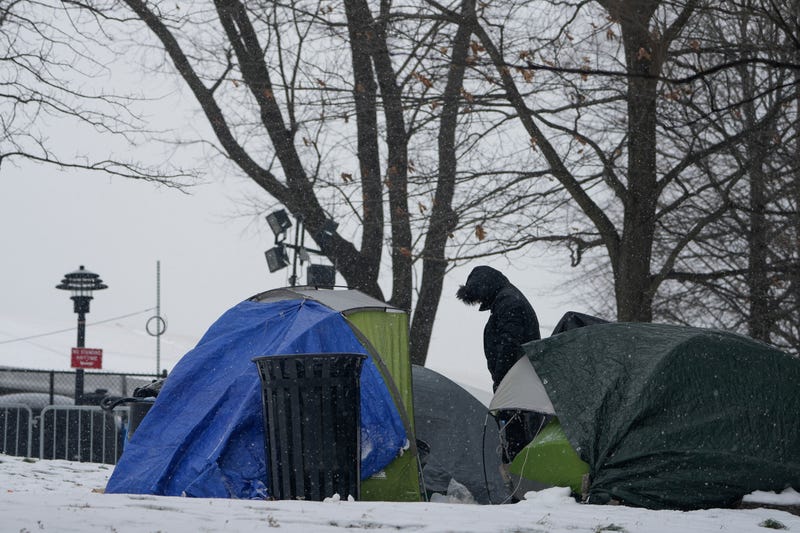 A man stands near a cluster of small tents pitched near a temporary shelter for migrants on Randall's Island in New York, Friday, Jan. 19, 2024