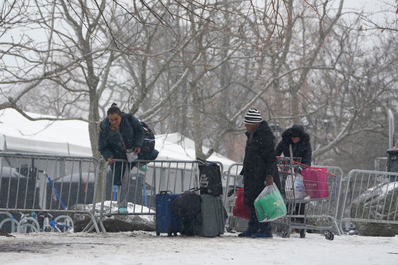 People hop a fence to get to a footbridge to Manhattan at a temporary shelter for migrants on Randall's Island in New York, Friday, Jan. 19, 2024