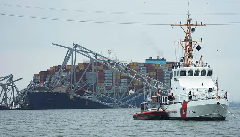 A Coast Guard cutter patrols in front of a cargo ship that is stuck under the part of the structure of the Francis Scott Key Bridge in Baltimore after the ship hit the bridge on Tuesday.