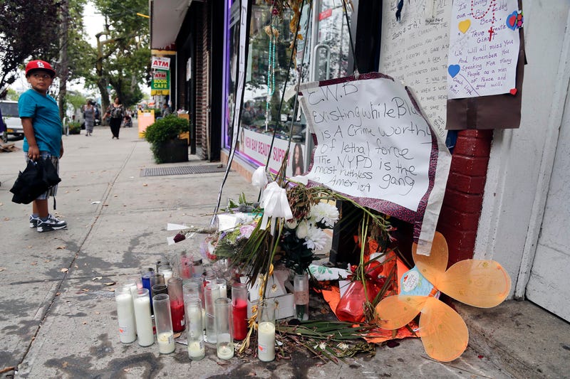 A young boy stops as he passes a makeshift memorial for Eric Garner, Friday, Aug. 1, 2014, on Staten Island