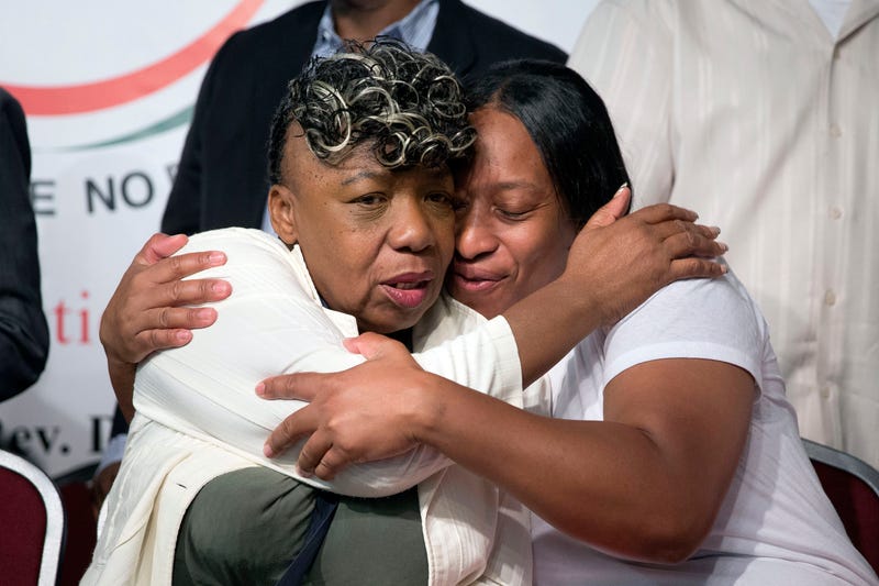 Gwen Carr, left, mother of Eric Garner, and his sister Ellisha Garner, hug during a rally at the National Action Network headquarters, July 26, 2014, in New York