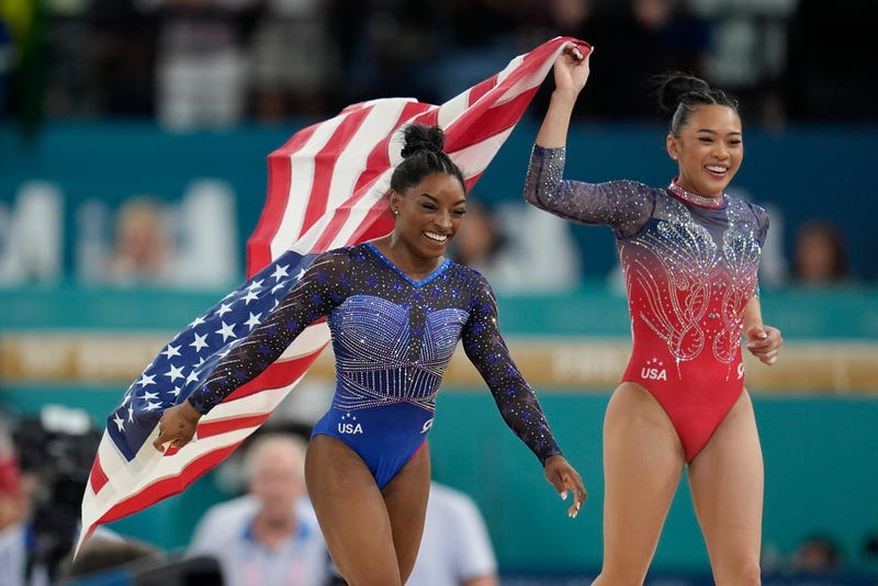 Simone Biles and Suni Lee celebrate winning medals in women's all-around at the Olympics.