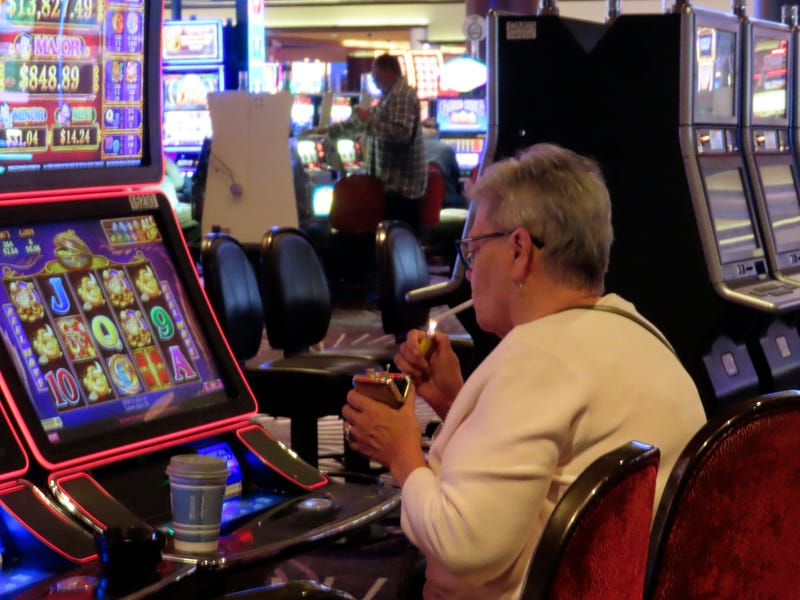 A gambler lights a cigarette at a slot machine in Harrah's casino in Atlantic City N.J., on Sept. 29, 2023.