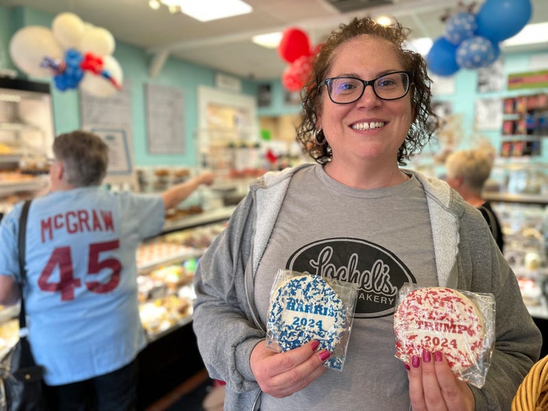 Bakery owner Kathleen Lochel holds sugar cookies, one with blue and white sprinkles and a Harris 2024 label on it and the other, with red and white sprinkles and a Trump 2024 label on it in Lochel Bakery, Tuesday, Sept. 24, 2024, in Hatboro, a suburb of Philadelphia.