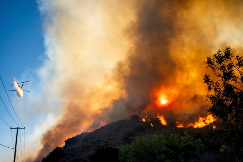 A helicopter drops water as the Mountain Fire burns along South Mountain Rd. on Thursday, Nov. 7, 2024, in Santa Paula, Calif.