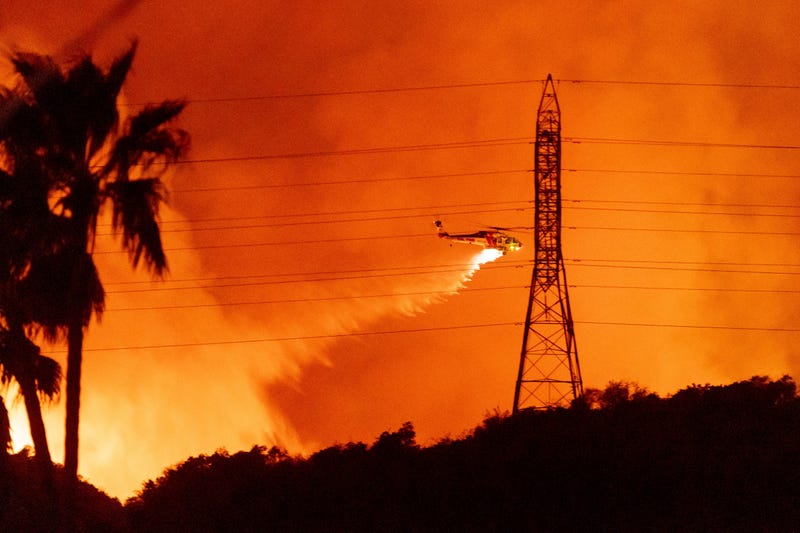 A helicopter drops water on the Palisades Fire in Mandeville Canyon, Friday, Jan. 10, 2025, in Los Angeles.