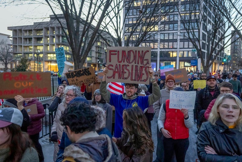 People protested in Washington, D.C., on Tuesday against a funding freeze of federal grants and loans following a push from President Donald Trump to pause federal funding.