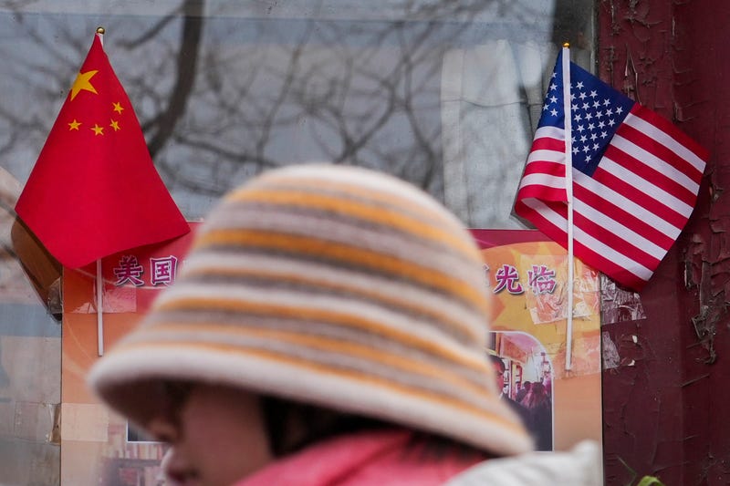 woman walks by the Chinese and U.S. national flags 