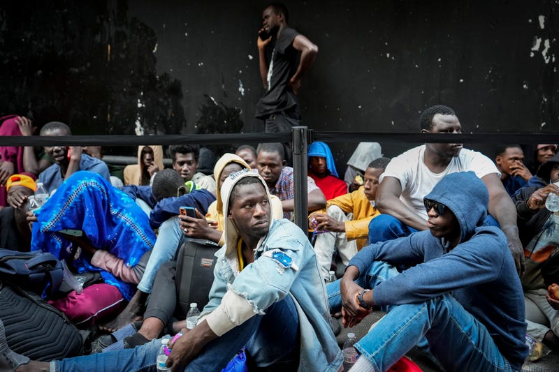 Migrants sit in a queue outside of The Roosevelt Hotel that was used by the city as temporary housing on Monday, July 31, 2023, in New York.
