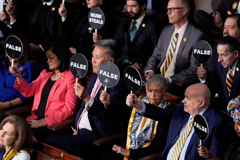 Members of Congress hold up signs as President Donald Trump addresses a joint session of Congress at the Capitol in Washington, Tuesday, March 4, 2025.