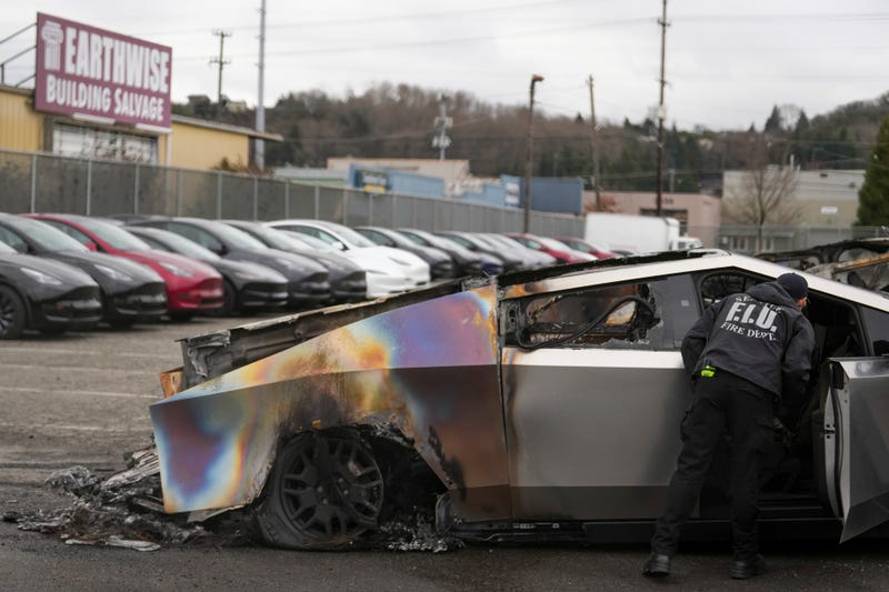 A member of the Seattle Fire Department inspects a burned Tesla Cybertruck at a Tesla lot in Seattle, Monday, March 10, 2025