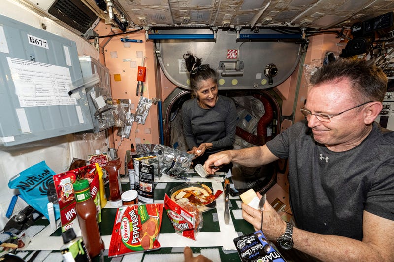 In this photo released by NASA, astronauts Suni Williams and Butch Wilmore, both Expedition 71 Flight Engineers, make pizza aboard the International Space Station's galley located inside the Unity module on Sept. 9, 2024. Items are attached to the galley using tape and velcro to keep them from flying away in the microgravity environment.