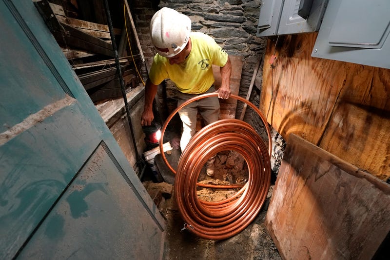 George Philbin, of Boyle & Fogarty Construction, works to feed a new copper residential water supply line, after removing an old lead residential water supply line, in the basement of a home where service was getting upgraded, June 29, 2023, in Providence, R.I.