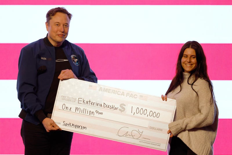 Elon Musk presents a check for $1 million during a town hall on March 30, 2025, in Green Bay, Wis.