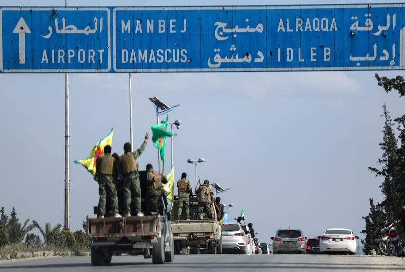 U.S.-backed Kurdish fighters stands on their vehicles, as they withdraw from two neighbourhoods in Syria's northern city of Aleppo as part of a deal with the Syrian central government, in Aleppo, Syria, Friday, April 4, 2025.
