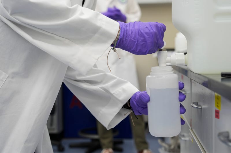 A water sample with forever chemicals, known as PFAS, into a container for research at a U.S. Environmental Protection Agency lab.