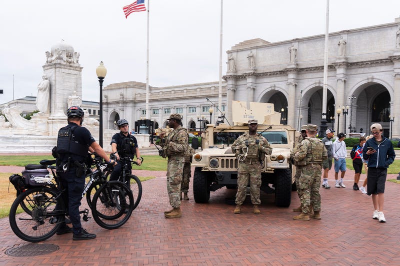 U.S. Capitol Police officers on bike patrol talk to District of Columbia Army National Guardsmen standing next to their Humvee military utility vehicle, outside Union Station near the U.S. Capitol in Washington, Tuesday, Aug. 19, 2025.