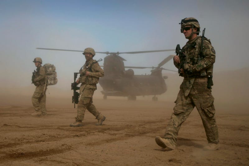 FILE - U.S. soldiers, part of the NATO- led International Security Assistance Force (ISAF), walk as a U.S. Chinook helicopter is seen on the back ground in Shindand, Herat, west of Kabul, Afghanistan, Jan. 28, 2012.