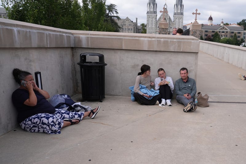 People shelter behind a wall on the Villanova University campus in Villanova, Pa., on Aug. 21, 2025, where an active shooter was reported. It was later deemed a hoax.