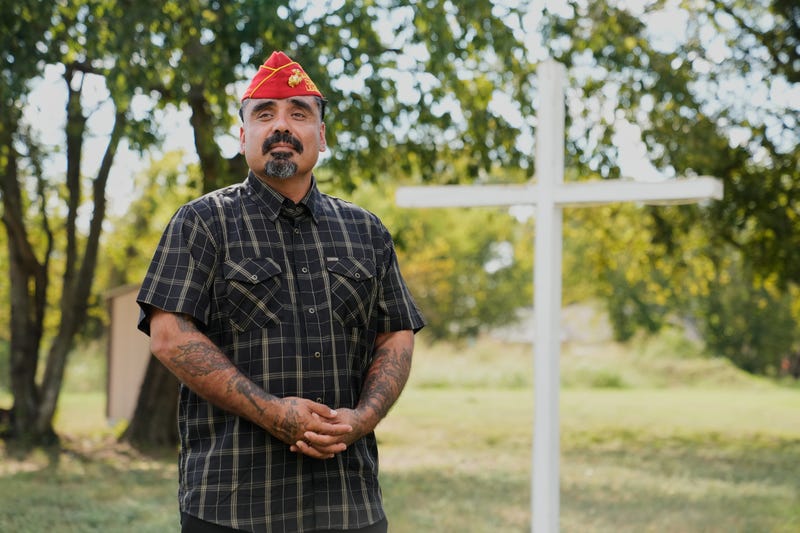 Julio Torres poses for a photo by a cross in an open field, Monday, Sept. 22, 2025, in Terrell, Texas.