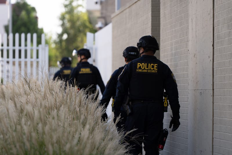 Department of Homeland Security officials walk to the gates of the U.S. Immigration and Customs Enforcement facility after inspecting an area outside on Sunday, Sept. 28, 2025, in Portland, Ore.
