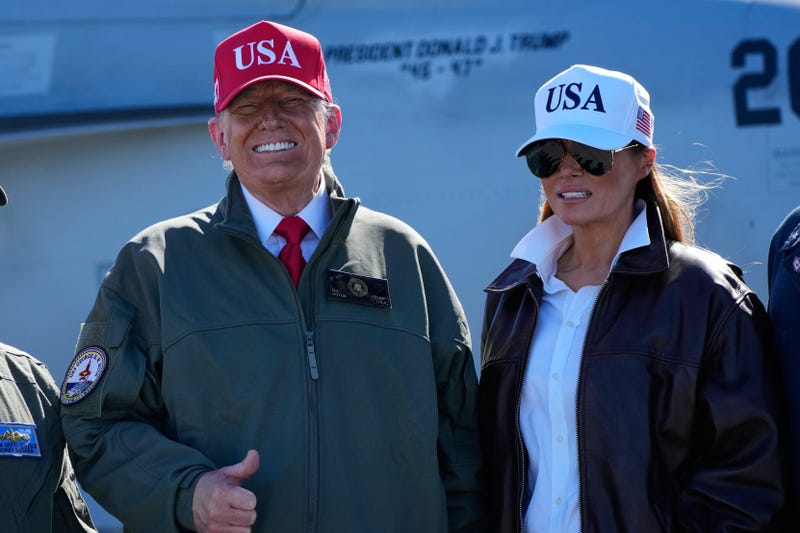 President Donald Trump and first lady Melania Trump pose in front of a F/A-18E fighter jet with President Donald Trump's name on it, as part of the Navy's 250th anniversary celebration, aboard the USS George H.W. Bush aircraft carrier in the Atlantic Ocean off the coast of Norfolk, Va., Sunday, Oct. 5, 2025.