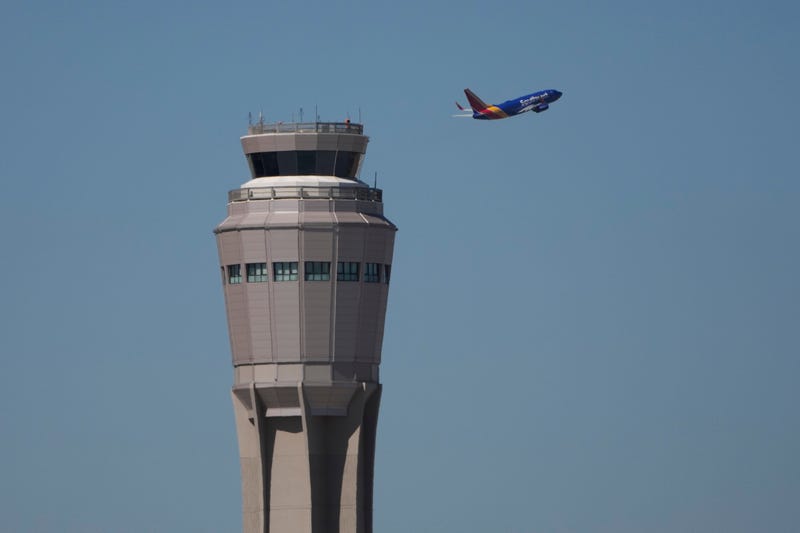 A plane takes off near the air traffic control tower at Harry Reid International Airport, Oct. 7, 2025, in Las Vegas.